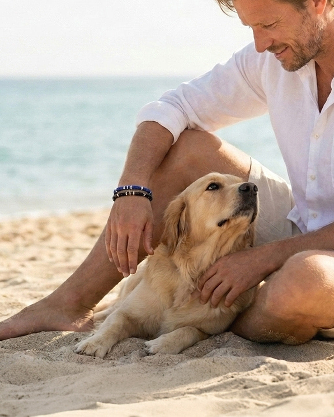 A quiet beach moment — man and golden retriever by the sea, wearing BeamMore lapis lazuli men's bracelet.